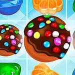 Fargerik sjokoladebelagt godteri med glitterperler omgitt av forskjellige typer gelé- og fruktgodteri på rad